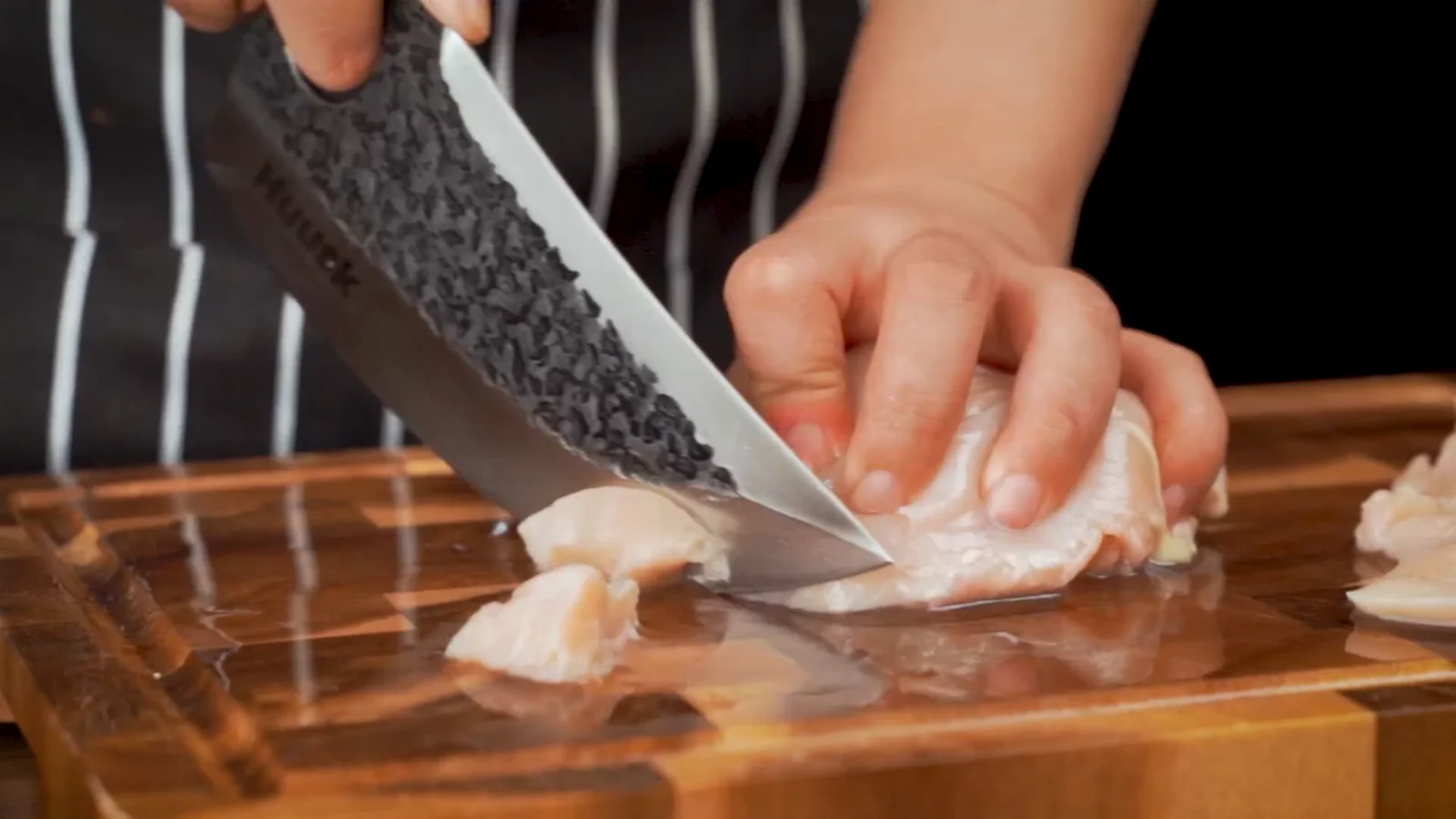 Chicken breast, held flat and sliced across. Raw protein gets its own board; the knife gets hot soapy water afterwards.
